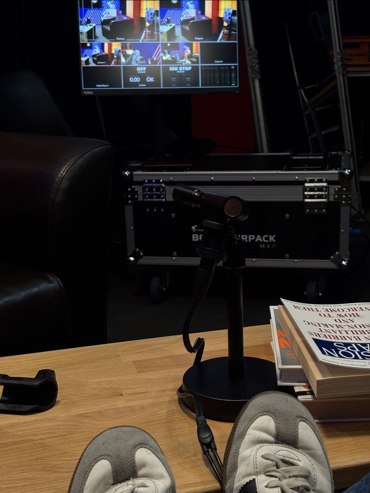 Behind the scenes: the production desk mid-shoot, a multiview monitor and a microphone on a stand.