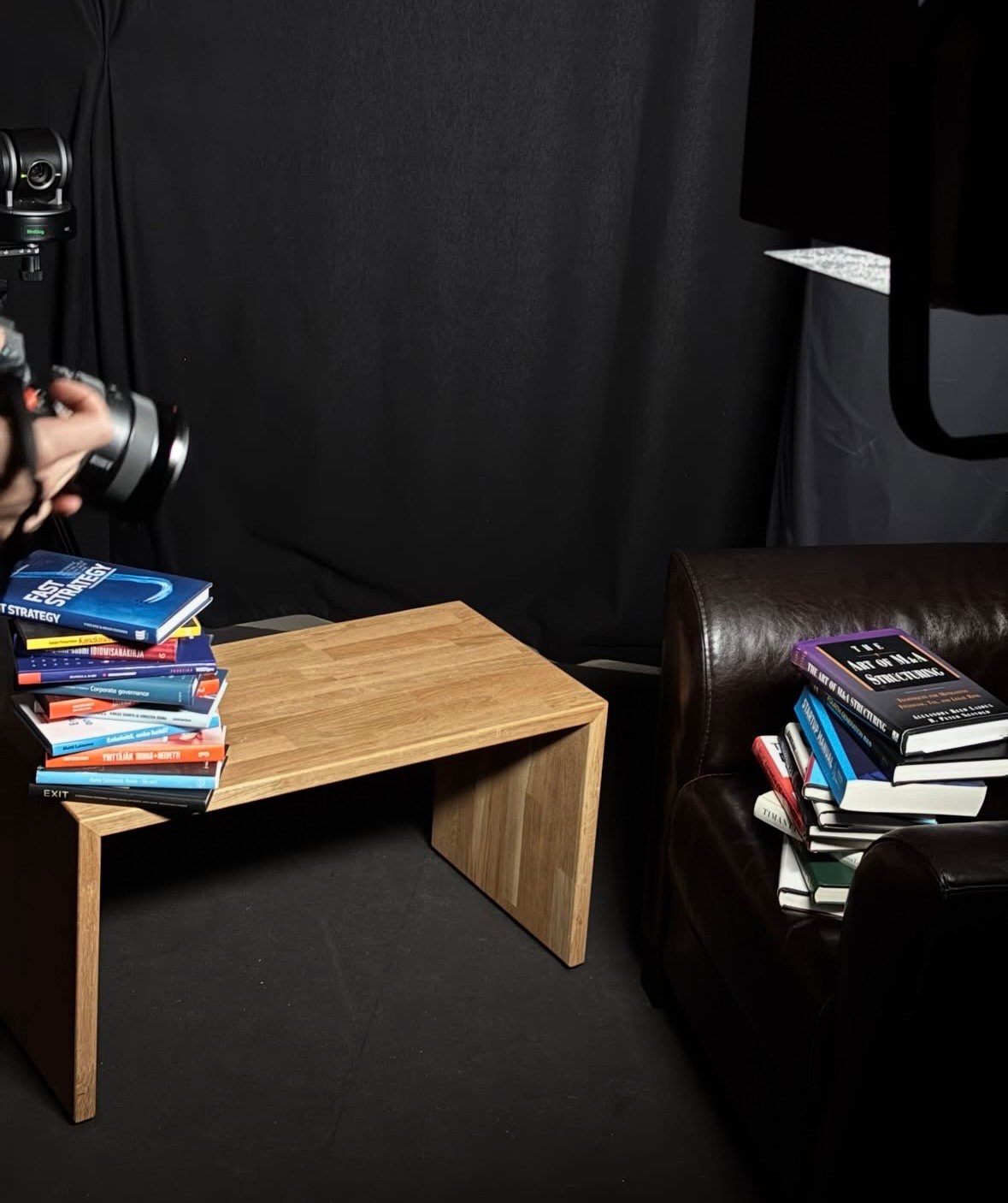 Behind the scenes: a blacked-out studio, stacks of strategy books, a wooden bench and a camera.